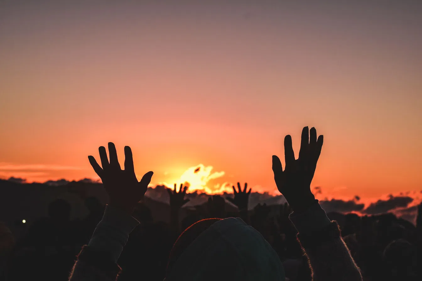Hands raised at sunset in worship